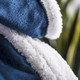 A soft, plush blanket featuring a deep blue exterior and a white fluffy lining.