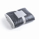 A grey plush blanket neatly folded and secured with a white band. The blanket features a soft texture and a contrasting underside.