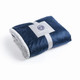 A folded navy blue blanket with a soft grey interior, secured with a branded band.