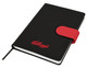 A black A5 notebook with a red elastic strap and a logo. The notebook features a ribbon bookmark and lined pages.