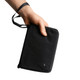 A black toiletry bag is held in a hand, featuring a zip closure and a wrist strap. It has a logo on the front.