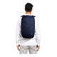 A person wearing a navy blue backpack, featuring padded shoulder straps and a simple design. The backpack has a logo.
