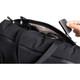 A black duffel bag with an open top revealing sunglasses and a small item being inserted.