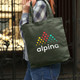 A green canvas tote bag with a multi-coloured logo and short handles, being held by a person.