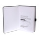 An A5 notebook with a black cover, featuring white recycled paper pages and a logo.