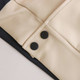 A close-up of a unisex varsity jacket featuring a cream and navy design with black buttons.