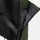 A soft-touch flap backpack in black and green, featuring a textured exterior and a patterned interior with pockets.