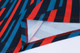 A vibrant 100% poly micro mesh long sleeve polo featuring a bold red and blue striped design with white detailing.
