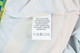 A care label on a 100% polyester micro mesh sports long sleeves shirt, featuring fabric care instructions.