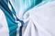 A fabric swirl featuring a pattern of teal and white stripes, showcasing polyester material suitable for fishing jackets.