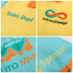 A colourful Hawaiian shirt featuring turquoise and yellow panels with various logos and text elements.