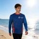 A long-sleeved blue sun protection T-shirt featuring red accents and a logo, worn by a model on the beach.