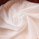 A close-up of soft, lightweight, white polyester fabric, showcasing its texture and drape.