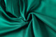 A vibrant green fabric, showcasing a smooth, soft texture ideal for sports shorts. The fabric has a subtle sheen.