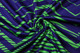 A vibrant navy and green patterned fabric, showcasing a wavy design with twisting folds.