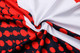 A close-up of a sublimated football jersey featuring a red, white, and black design with circular patterns and a logo.