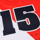 A red and white football jersey featuring a large black number 15 and a logo. Made from 100% polyester.