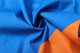 A vibrant fabric with blue and orange sections, showcasing soft and smooth cotton texture, suitable for shirts.