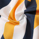 A close-up of fabric featuring a pattern with yellow, white, and navy stripes, showcasing a soft, silky texture.