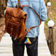 A colourful pyramid-shaped puzzle attached to a brown leather backpack, hanging from a keyring.