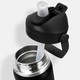 A drink bottle in black with a flip straw and stainless steel interior, featuring a lid with a logo.