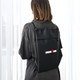 A black drawstring bag with a logo, worn on the back of a person, featuring a sleek design.