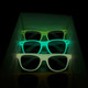 Glow in the dark sunglasses in green shades, stacked inside a display box. The sunglasses emit a soft glow in the dark.
