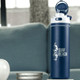 A drink bottle made of recycled stainless steel, featuring a navy blue colour and a flip straw lid. It has a logo.