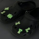 Black clog shoes adorned with green glowing charm letters and symbols for a fun and novelty look. Black clog shoes adorned with green glowing charm letters and symbols for a fun and novelty look.