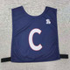 A navy blue pull-over elastic netball bib with a large white ‘C’ and a branding logo. A navy blue pull-over elastic netball bib with a large white ‘C’ and a branding logo.