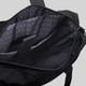 A black tote bag with an interior featuring a patterned lining and compartments for organisation. It has a logo.