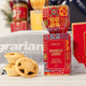 A festive gift set featuring a box of gingerbread almonds with decorative packaging and mini pastries in the foreground.