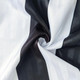 A close-up of a fabric featuring alternating black and white stripes, showcasing a smooth texture.