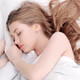 A young woman with long hair sleeps peacefully, wearing bright yellow ear plugs in her ears.