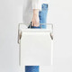 A white metal ice cooler box with a silver handle being held by a person in blue jeans. It features a logo.