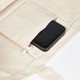A large cream canvas tote bag with a black smartphone tucked into a zippered pocket.