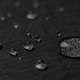 A close-up of water droplets on a textured black fabric, highlighting its water-resistant properties.