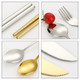 A stainless steel fork, spoon, and chopsticks in silver and gold, accompanied by a red tomato on a white background.