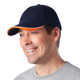 A navy blue cap with an orange accent, featuring a logo, being worn by a smiling man.