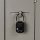 A black TSA lock secured to a grey locker, featuring a combination dial and a small logo.