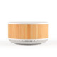 A round speaker and wireless charger with a bamboo timber exterior and a white base. The product features a logo.