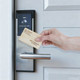 A bamboo business card is being held near a contactless door lock with a sleek silver handle.