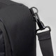 A black travel backpack with a textured surface, featuring a clip attachment and adjustable strap.