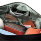 A black duffel bag interior featuring various items, including a pair of sunglasses, a notebook, and orange pouches.
