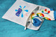A white laundry bag with a logo, featuring colourful patterned socks peeking out from the zippered opening.