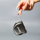 A black tape measure is being held by a hand, showcasing its sleek design and branding.