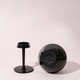 A black detachable wine glass with a round base and a separate stem, set against a light background.
