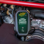 Battery Tender 022-0196 6V charger sitting in the engine bay of a red vehicle with its status LED lit