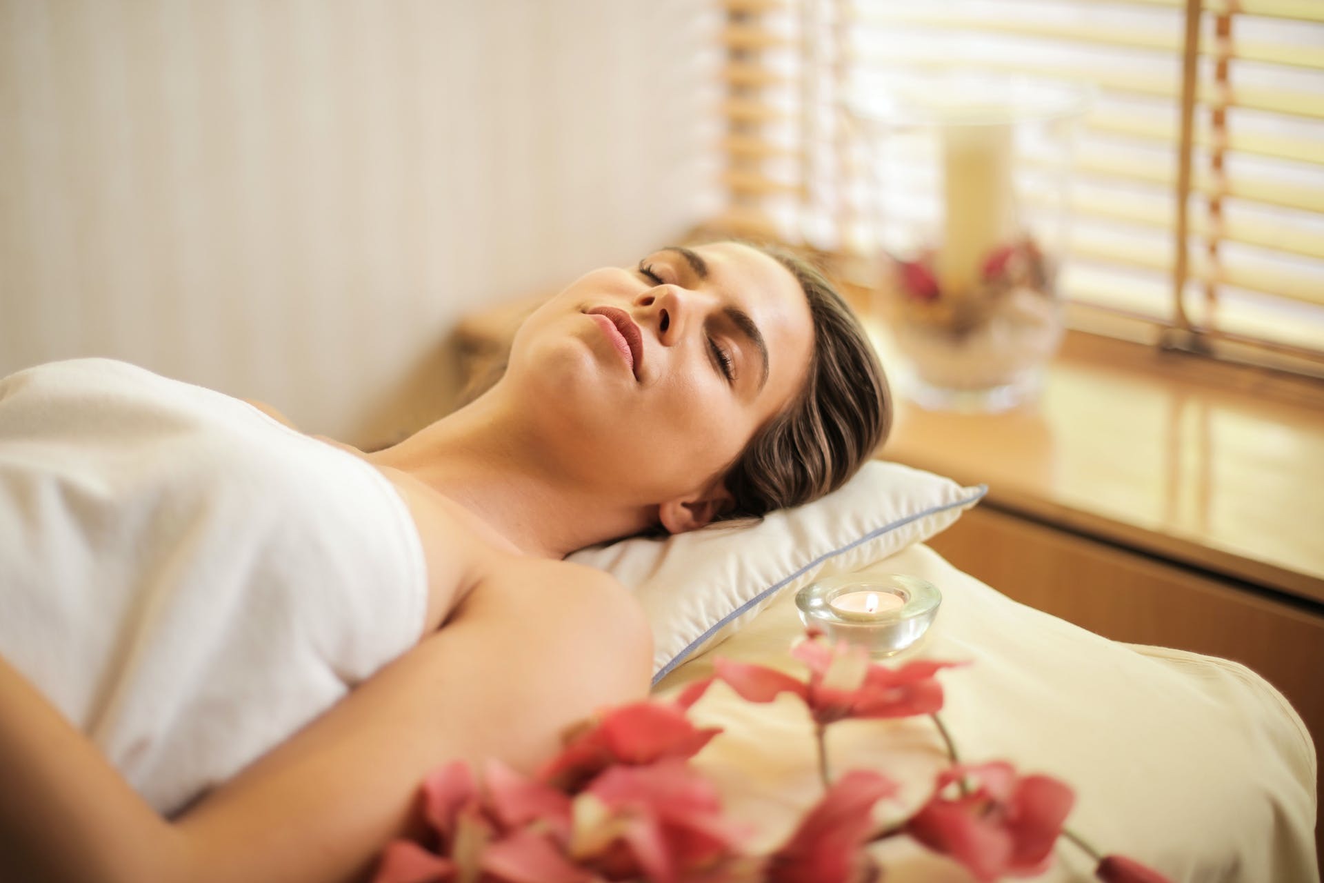 Woman lying on salon table with flowers and candles