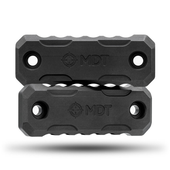Frontal view of two black MDT M-LOK exterior forend weights, model 107304-BLK, stacked directly above each other. These precision rifle accessories are designed to add weight for balance enhancement, featuring a robust construction with M-LOK mounting system compatibility. Each weight displays the engraved MDT logo, set against a pure white background to emphasize their sturdy, geometric design.